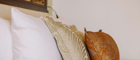 A bed with three pillows of different patterns and colors.