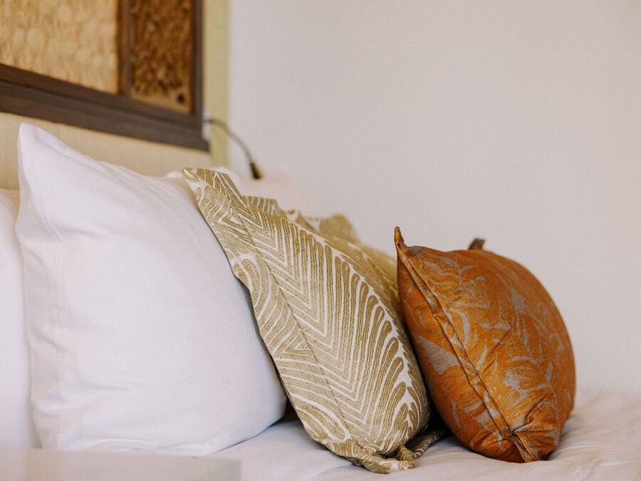 Uma cama com três almofadas de diferentes padrões e cores.