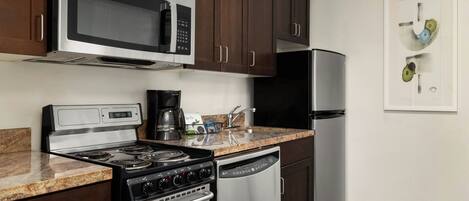 A kitchen with dark wooden cabinets, stainless steel appliances including a microwave, stove, dishwasher, and refrigerator.
