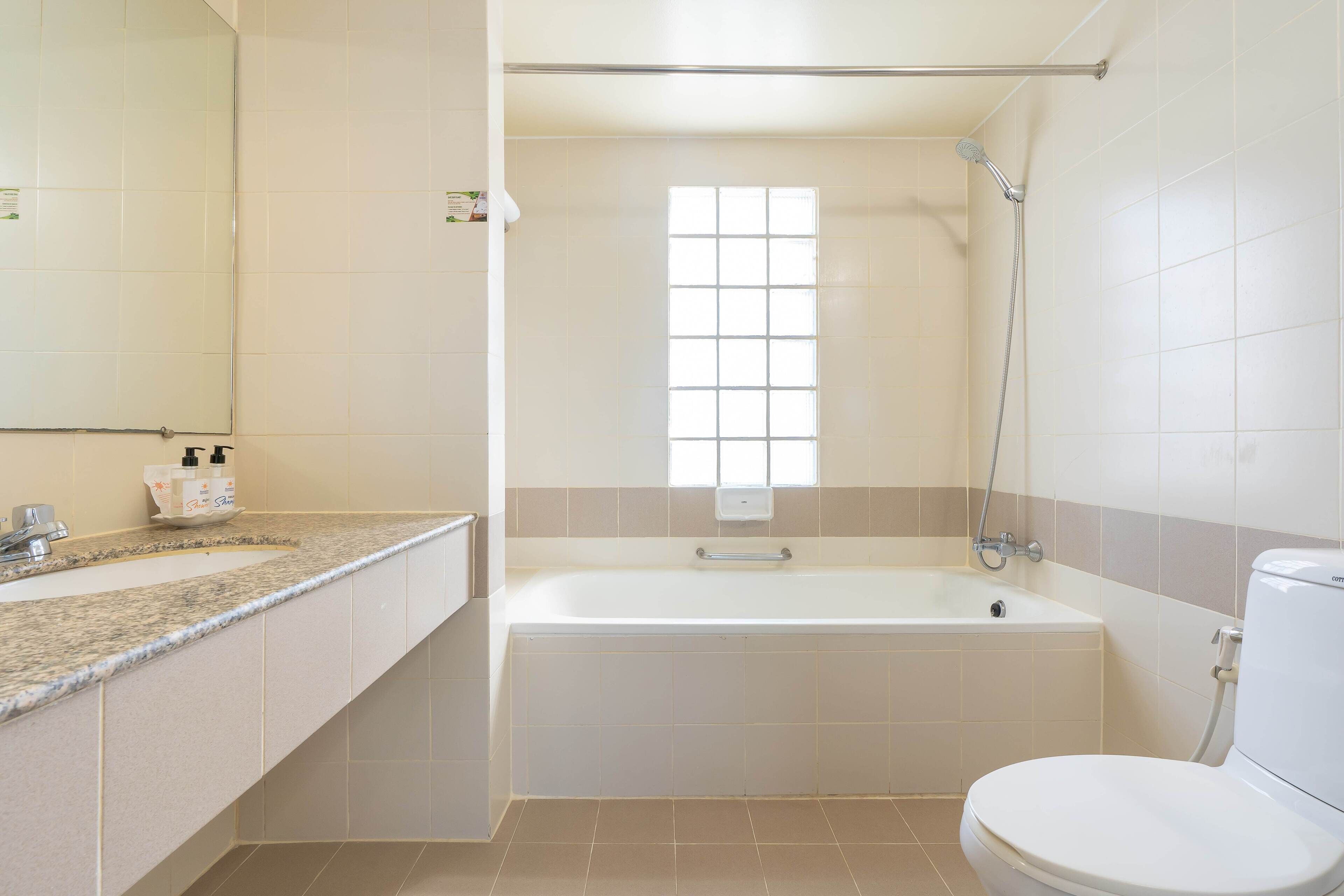 A bathroom with a bathtub, toilet, sink, and a window.