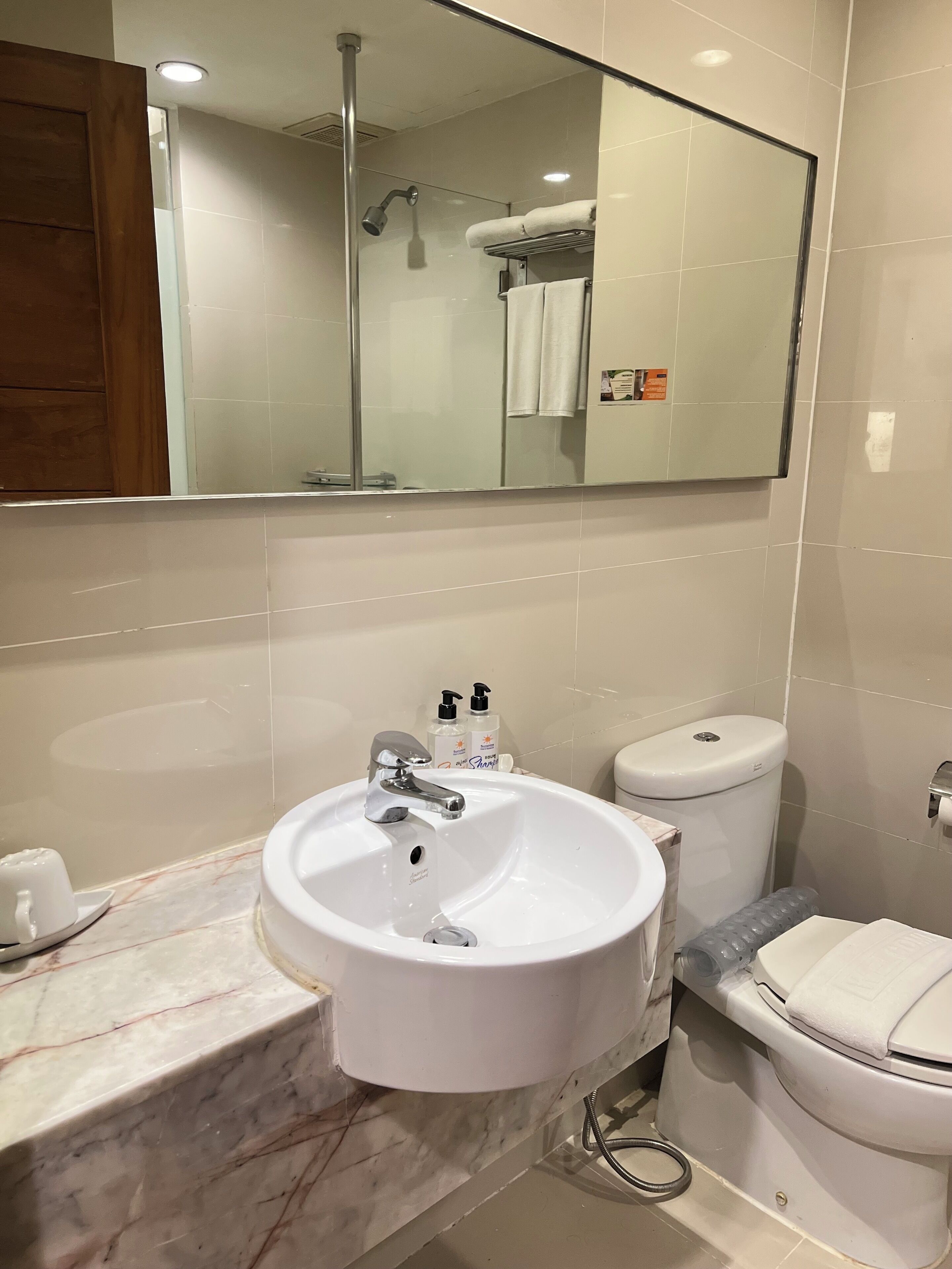 Une salle de bain avec un lavabo blanc, un miroir et des toilettes.