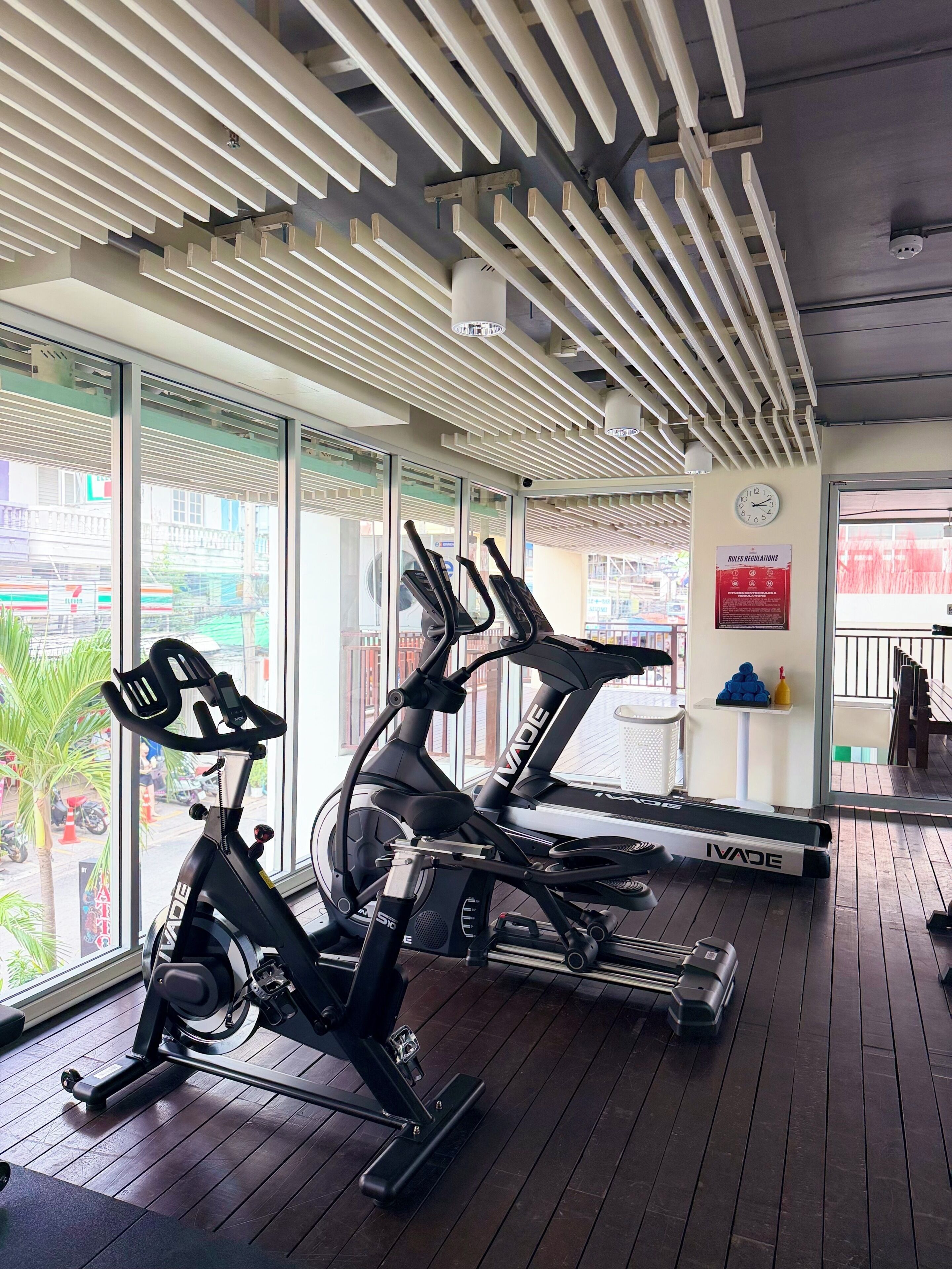 A gym with two stationary bikes, a clock, and a 'Rules Regulations' sign.