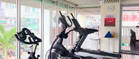 A gym with two stationary bikes, a clock, and a 'Rules Regulations' sign.