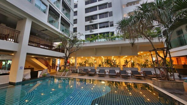 A hotel with a central swimming pool, multiple balconies, and indoor plants. - Sunshine Hotel And Residences (Pattaya)