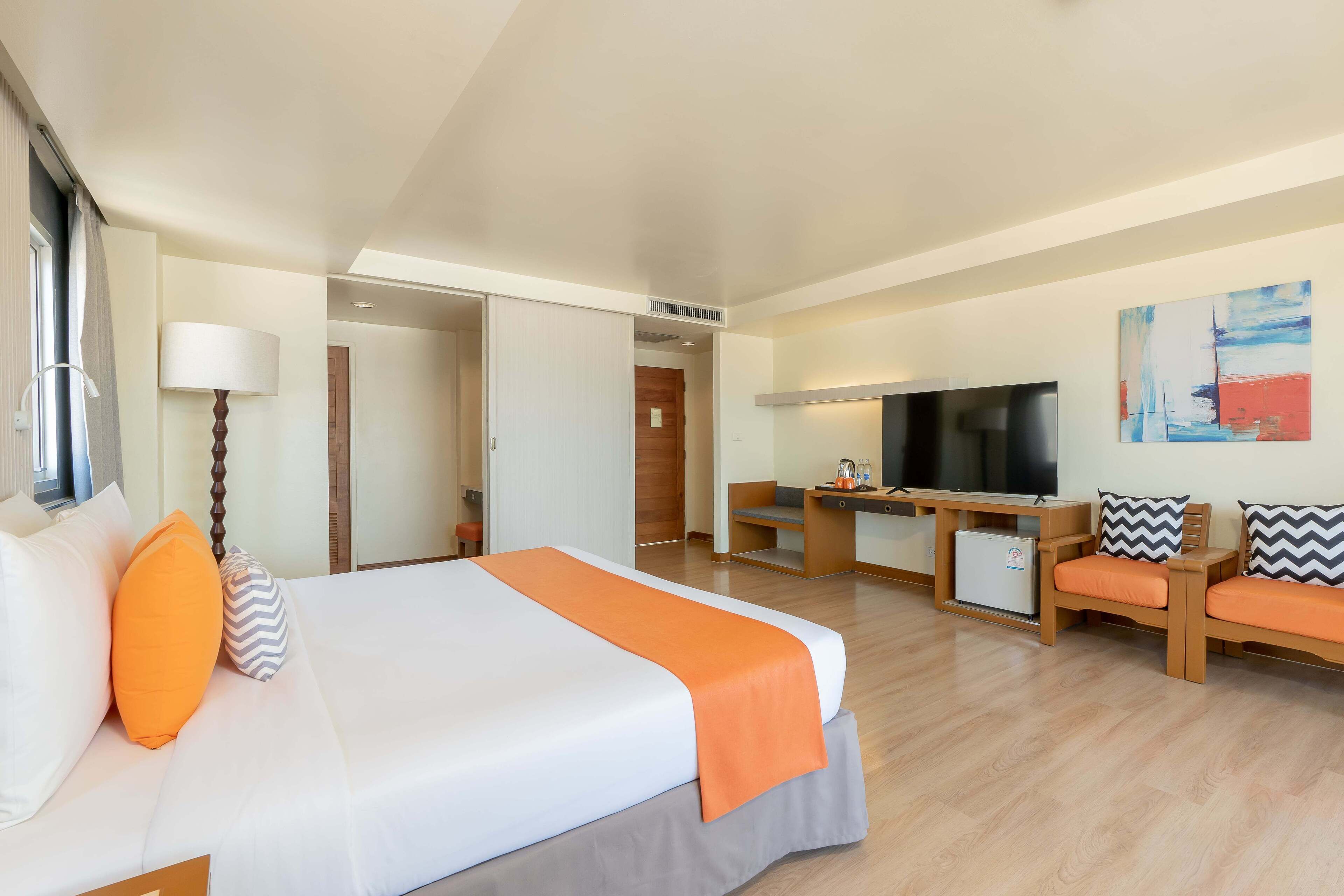 Una camera d'albergo con un letto, una scrivania, una TV e un’area salotto.