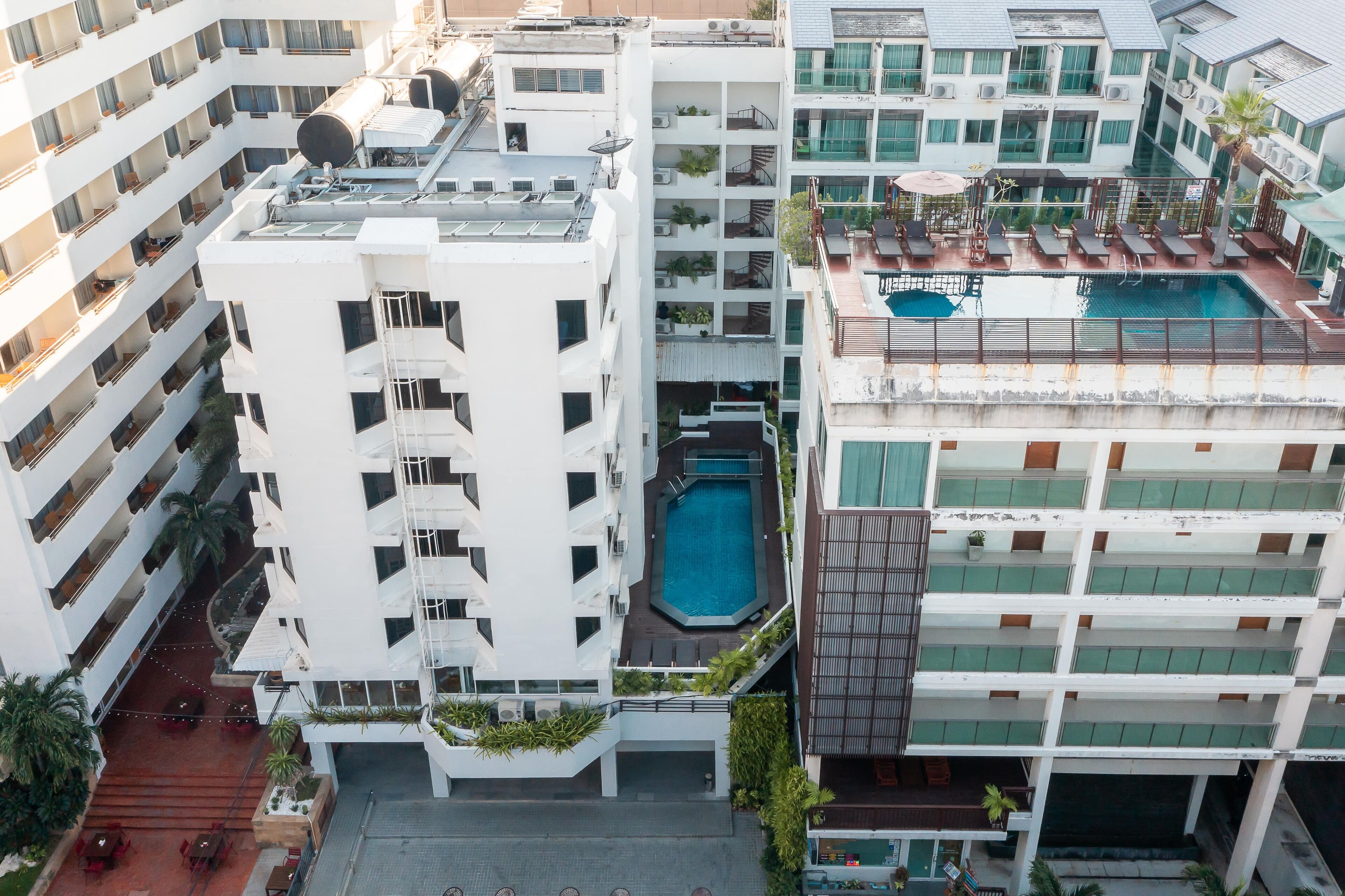 A multi-story hotel with a rooftop pool, balconies, and outdoor seating areas.