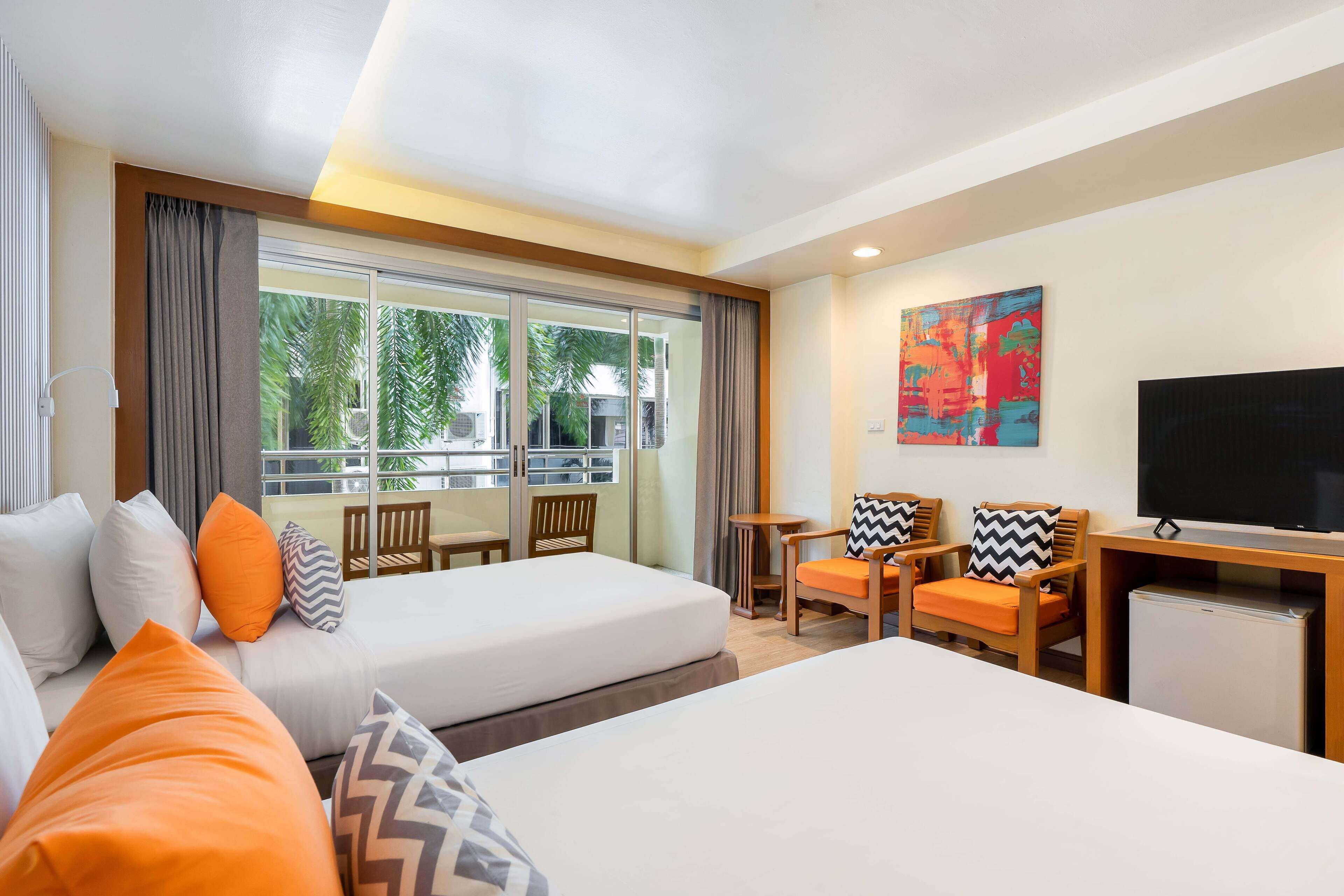 A hotel room with two beds, a TV, a small table, and a window with curtains.