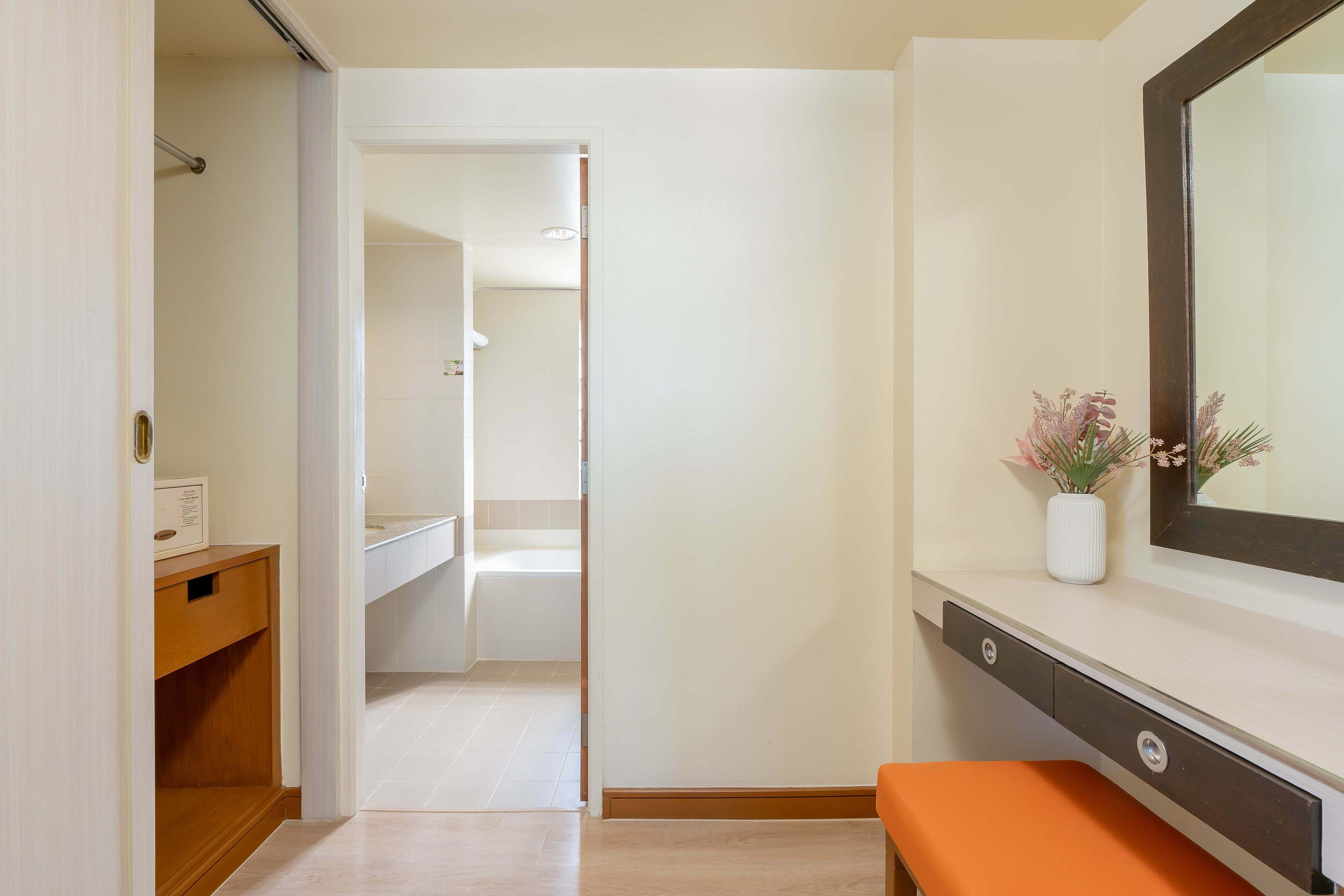 A bathroom with a white sink, a mirror, and a small vase with flowers.