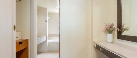 A bathroom with a white sink, a mirror, and a small vase with flowers.