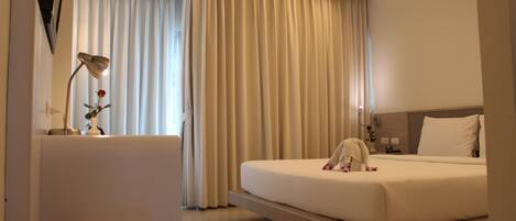 A hotel room with a bed, bedside table, lamp, and curtains.