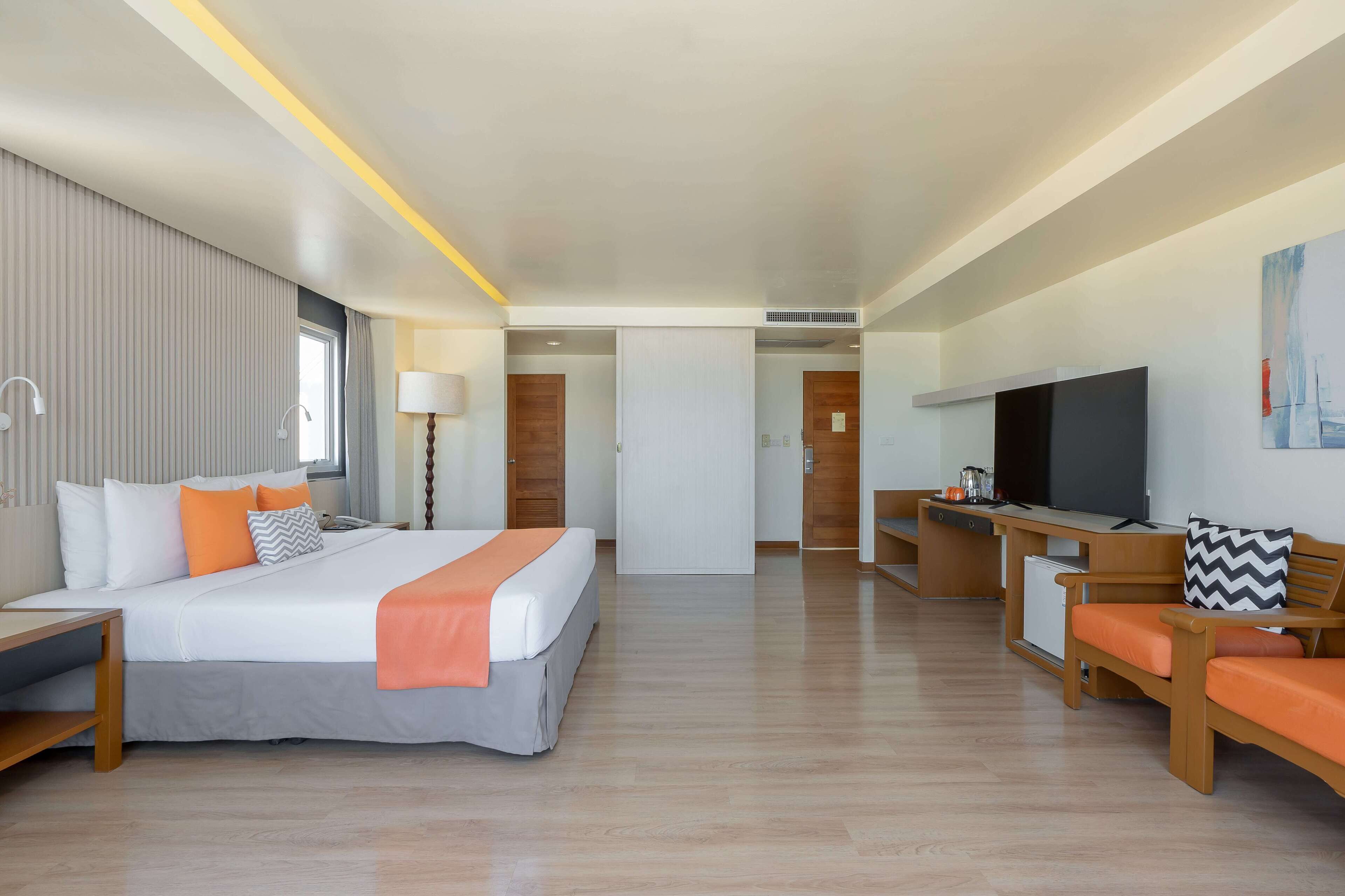 Habitación de hotel con cama, escritorio, televisión y zona de estar.