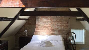 Un dormitorio con una cama, una silla, una mesita de noche y una pared de ladrillo.