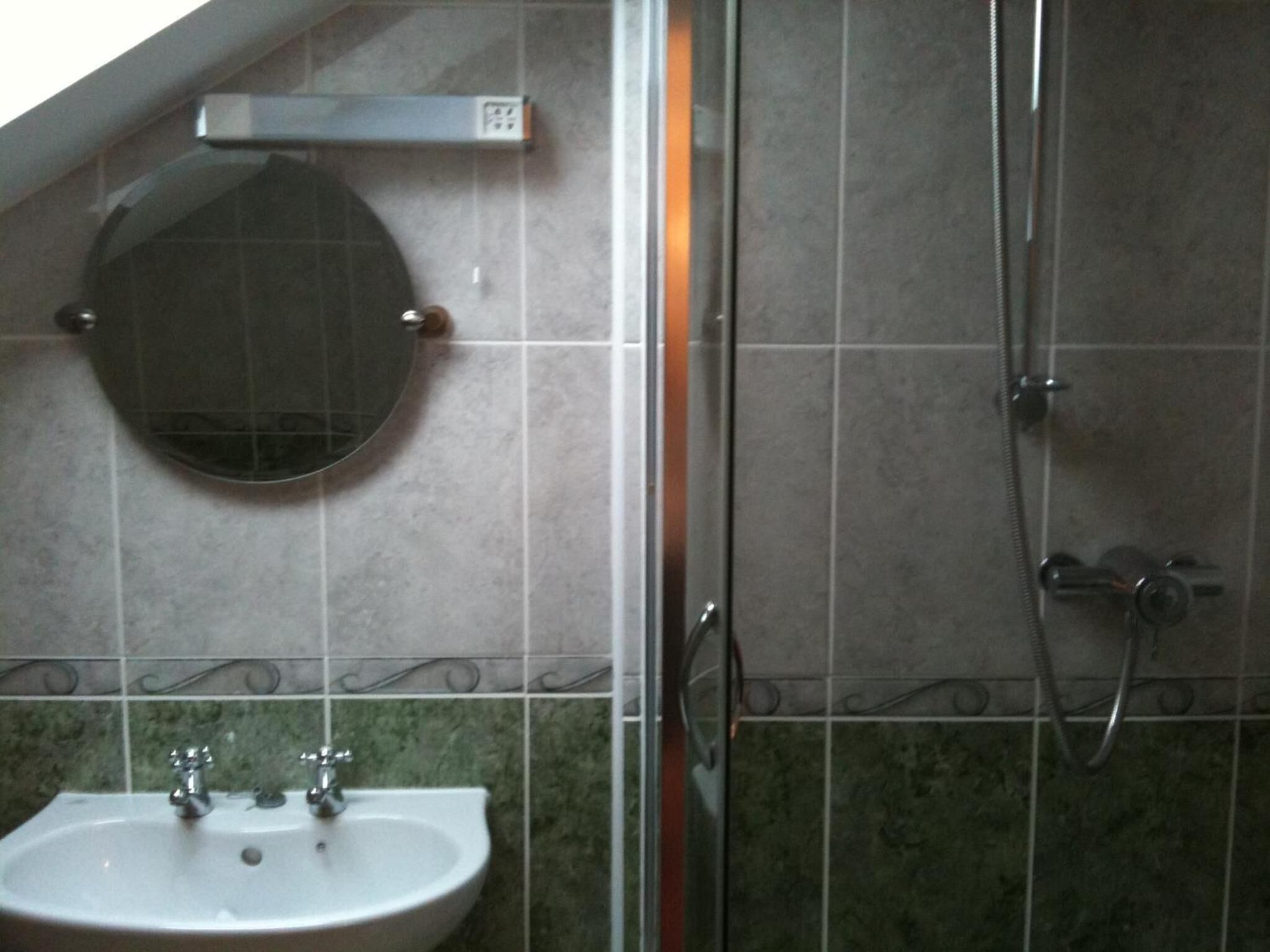 Baño con lavamanos, espejo y ducha.