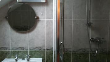Baño con lavamanos, espejo y ducha.
