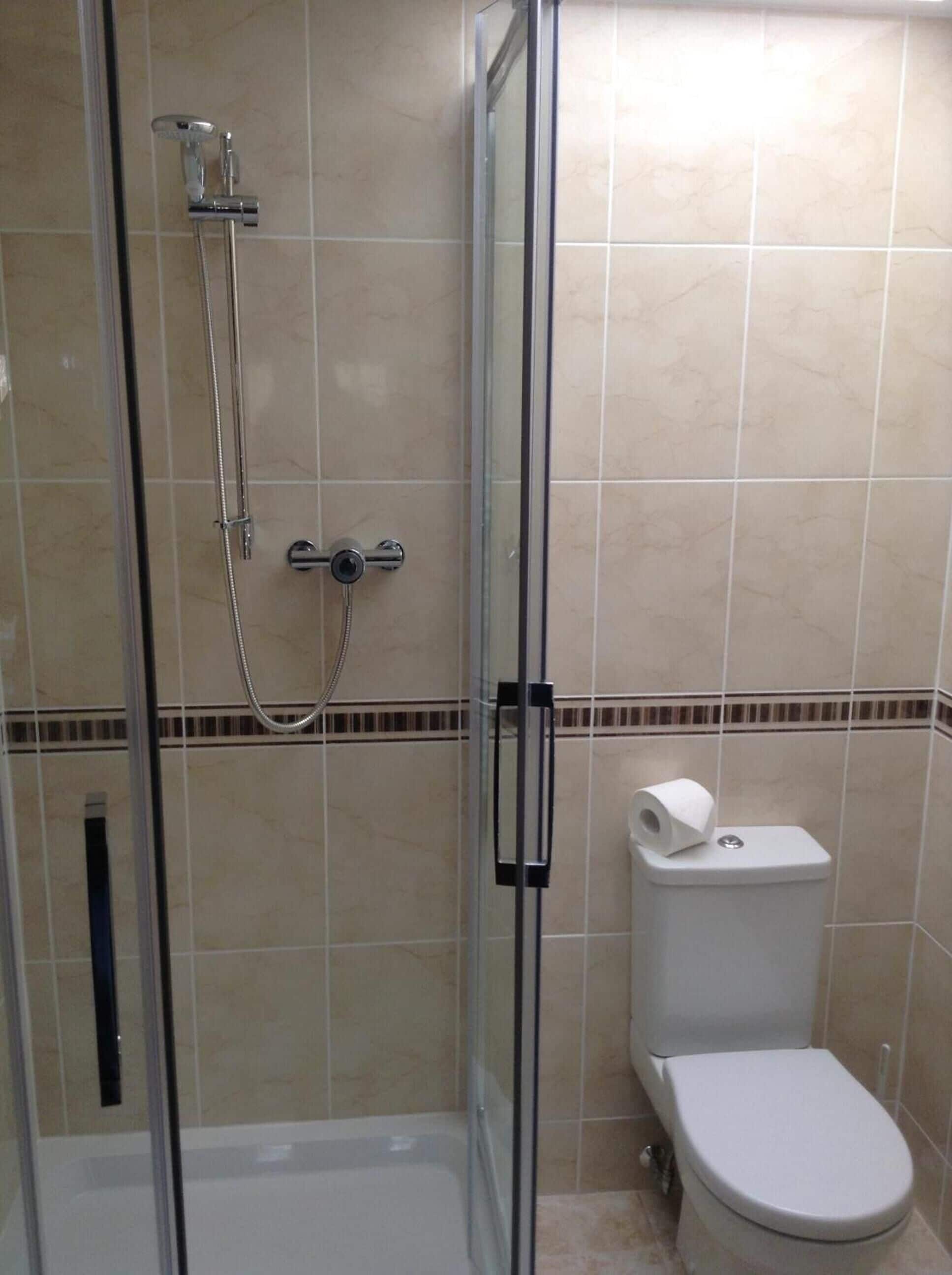 A bathroom with a glass shower enclosure, a toilet, and a bidet.