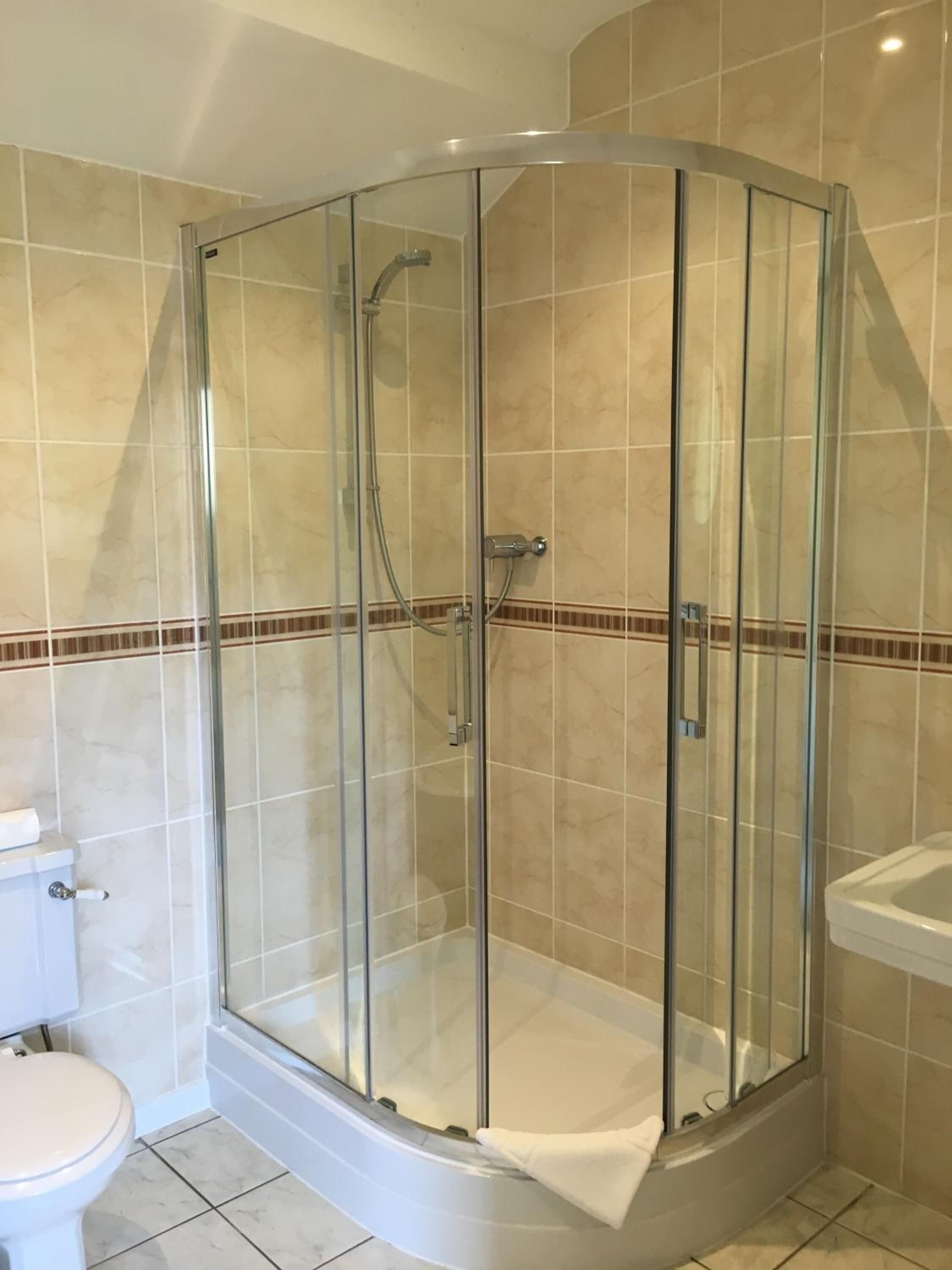 Une cabine de douche d’angle avec des portes en verre, des toilettes et un lavabo.