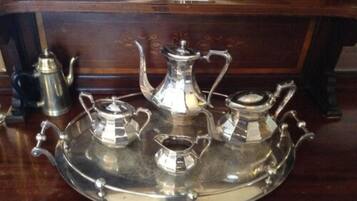 A silver tray with three matching teapots and a creamer on a wooden surface.
