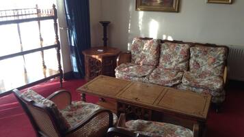 A traditional living room with a wooden coffee table, floral upholstered sofa, and wicker chairs.