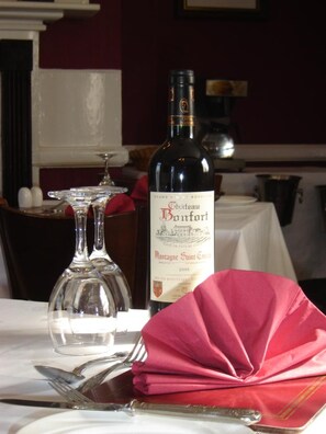 A bottle of Château Banzart wine, a glass, and a folded napkin on a table. - The Crown Hotel (Thetford)