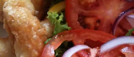 Un plato con comida frita, rodajas de tomate y lechuga.