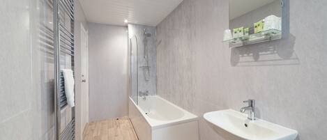 A modern bathroom with a glass-enclosed shower, a freestanding bathtub, and a pedestal sink.