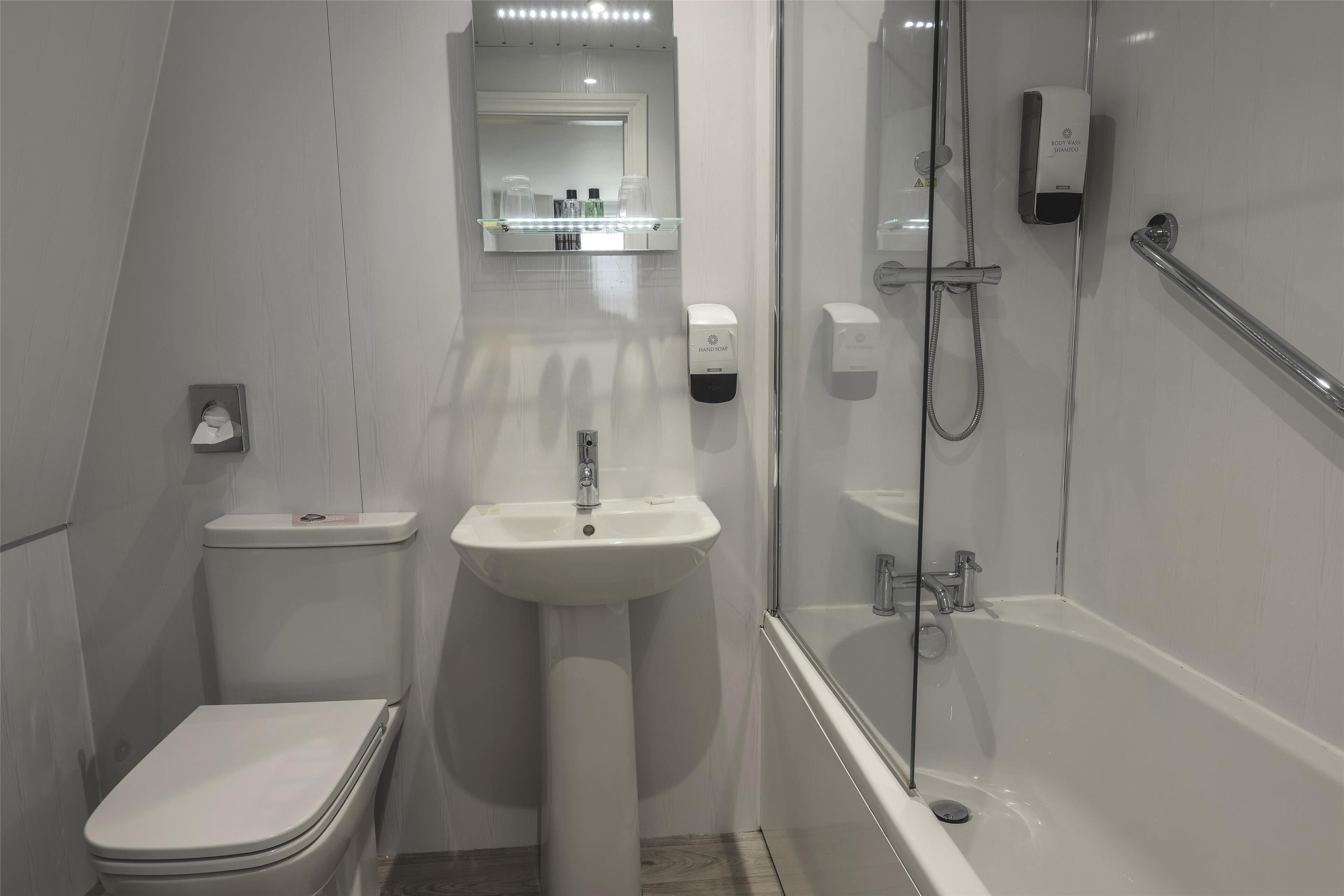 Un baño moderno con inodoro, lavamanos y ducha.