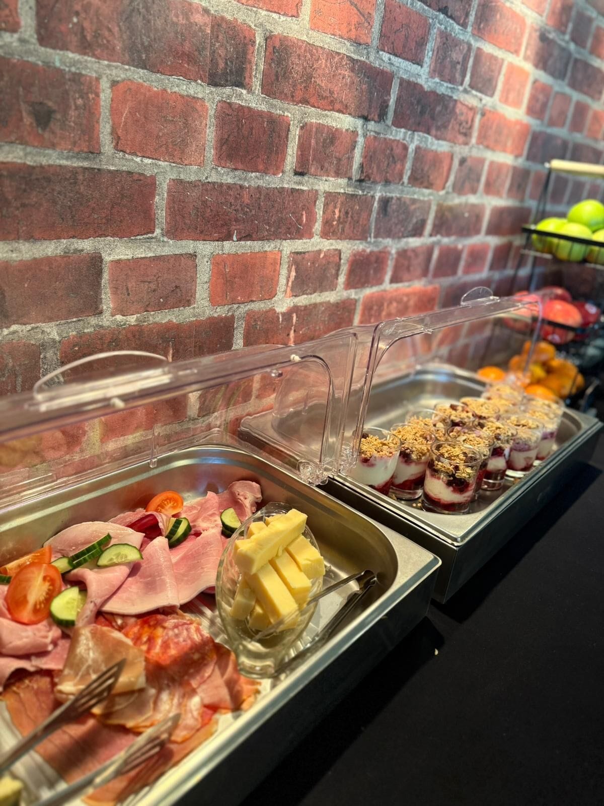 A buffet with various food options including meats, cheeses, and desserts.