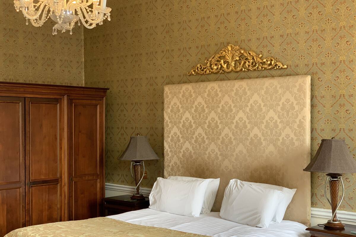 A neatly arranged bedroom with a large bed, a wooden wardrobe, and two bedside lamps.