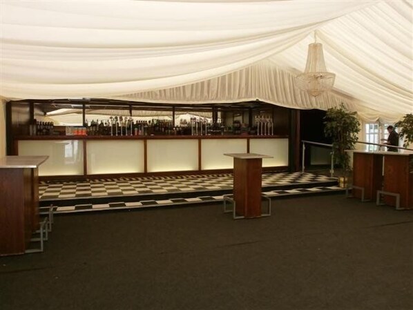 A bar area with a checkered floor, wooden bar counters, and a hanging light fixture.