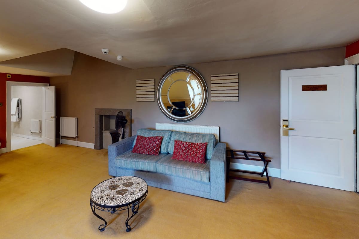 A living room with a sofa, a round mirror, a small table, and a door.