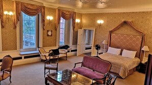 A spacious bedroom with a four-poster bed, a glass-top coffee table, two armchairs, and a chaise lounge. - Colwick Hall Hotel (Nottingham)