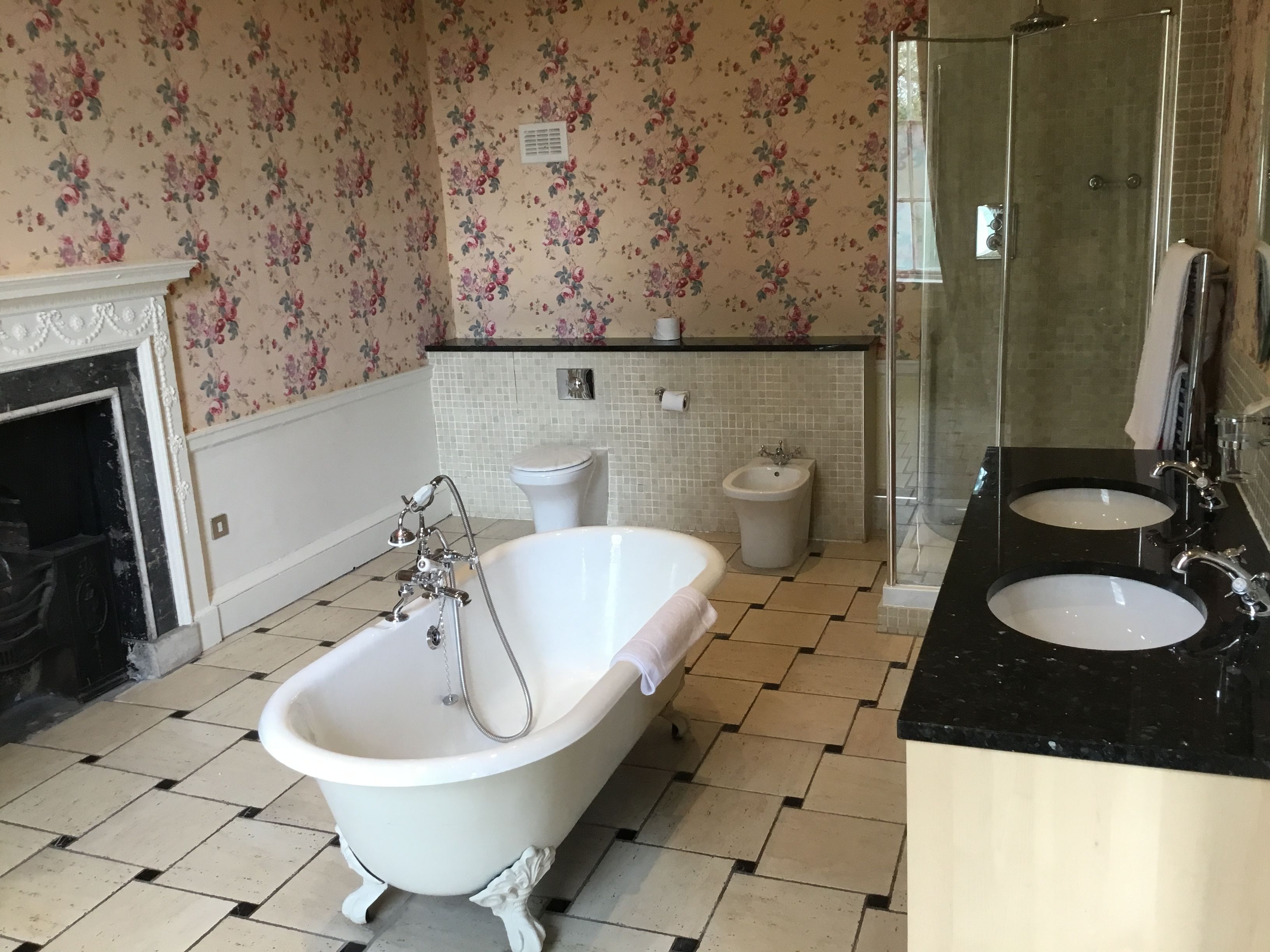 A bathroom with a clawfoot bathtub, a bidet, a toilet, and a glass-enclosed shower.