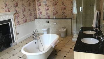 A bathroom with a clawfoot bathtub, a bidet, a toilet, and a glass-enclosed shower.