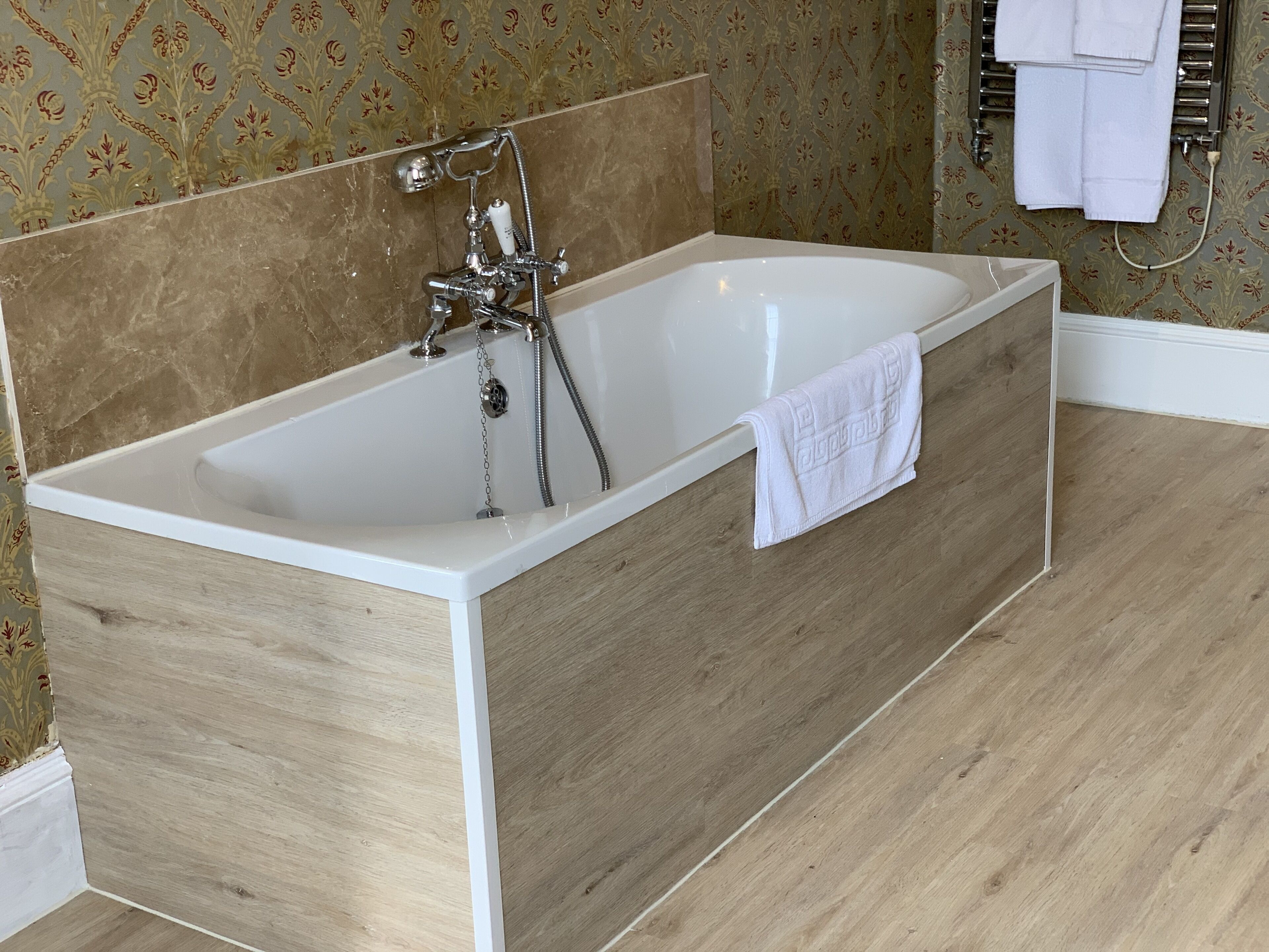 A modern bathroom with a freestanding bathtub, a showerhead, and a towel rack.