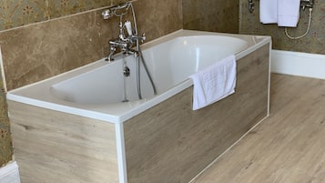 A modern bathroom with a freestanding bathtub, a showerhead, and a towel rack.