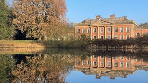A large brick building with a symmetrical facade and a reflection in the water. - Colwick Hall Hotel (Nottingham)
