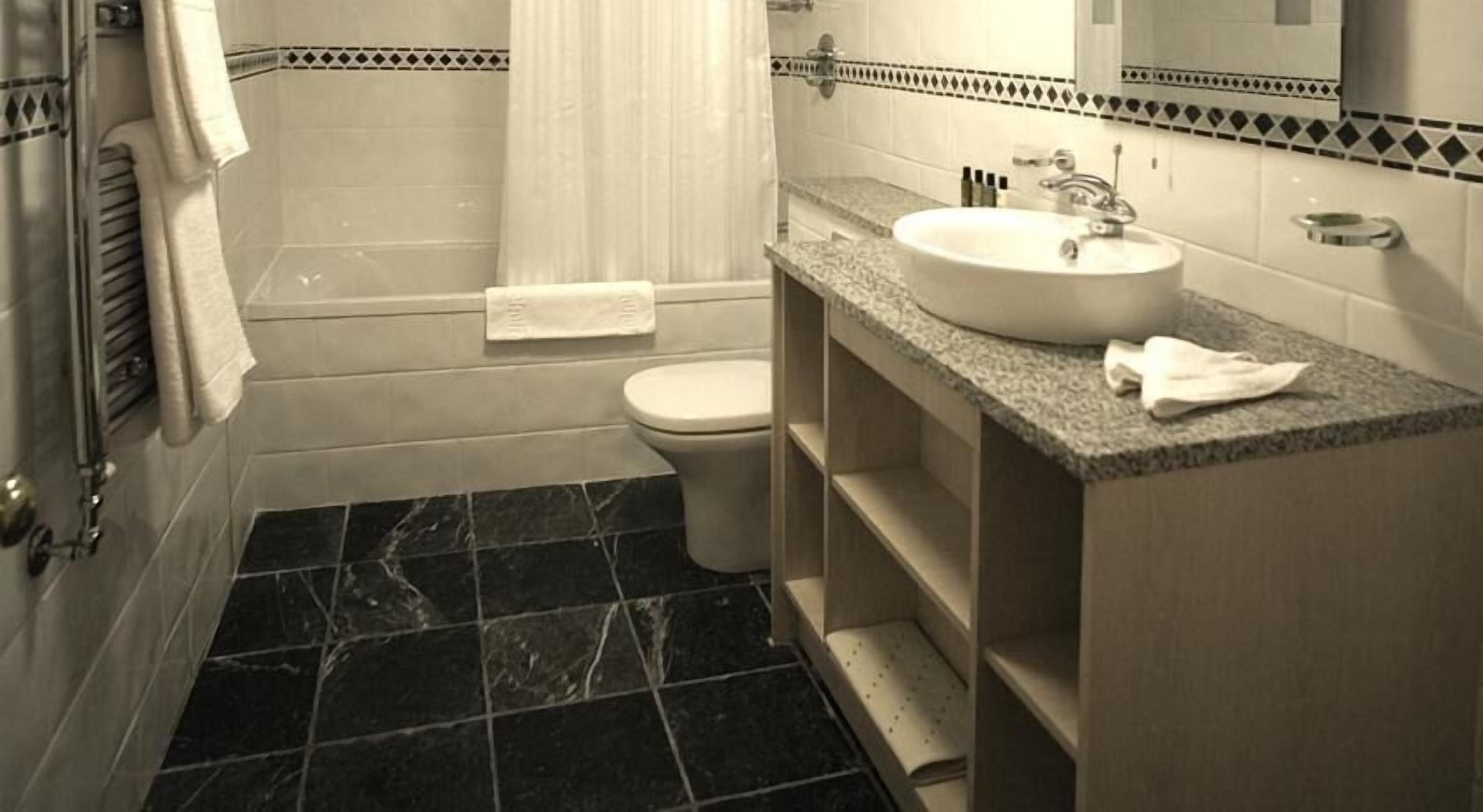 A bathroom with a toilet, sink, and shower.