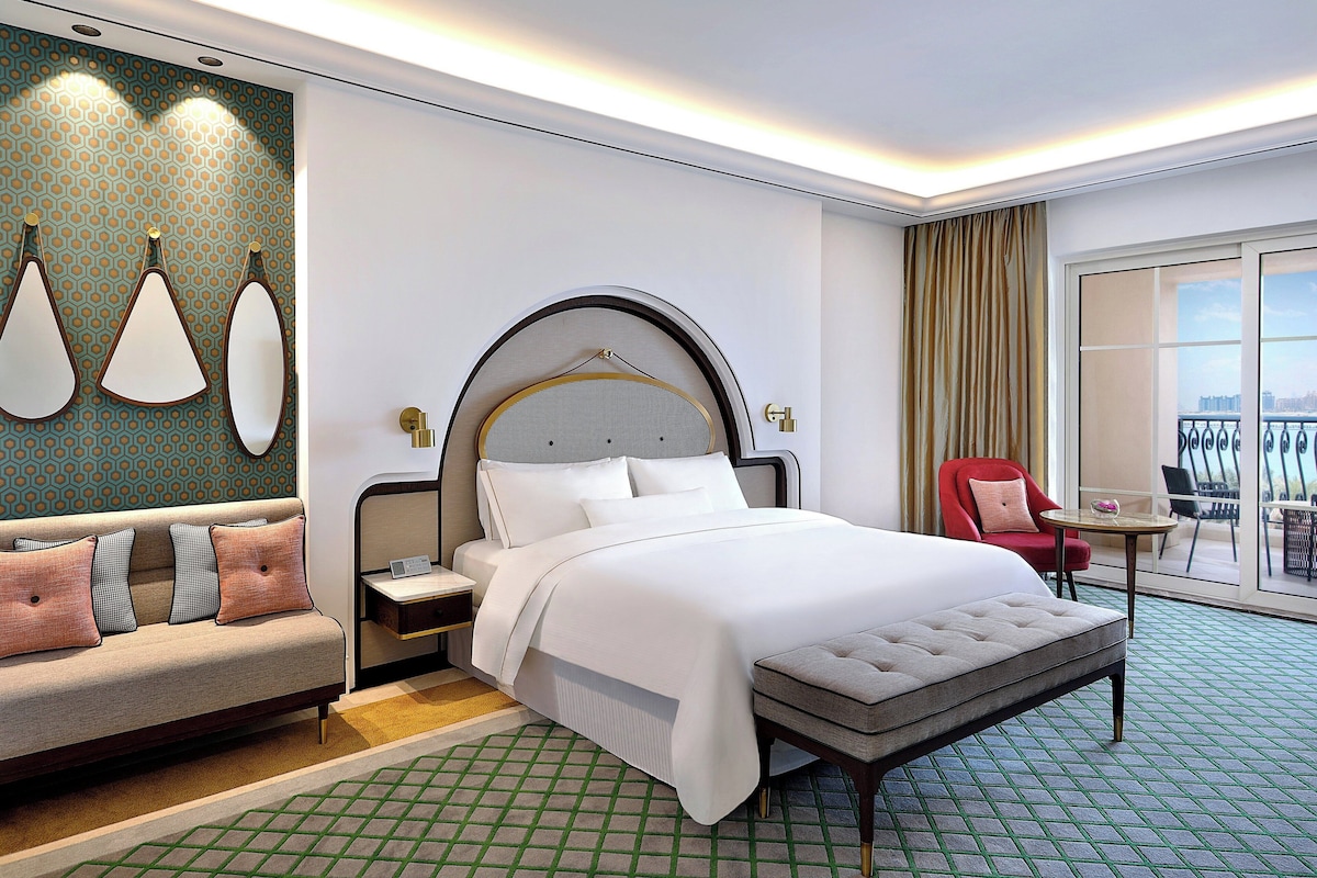 Une chambre d’hôtel avec un grand lit, un canapé, une petite table et un balcon avec vue.