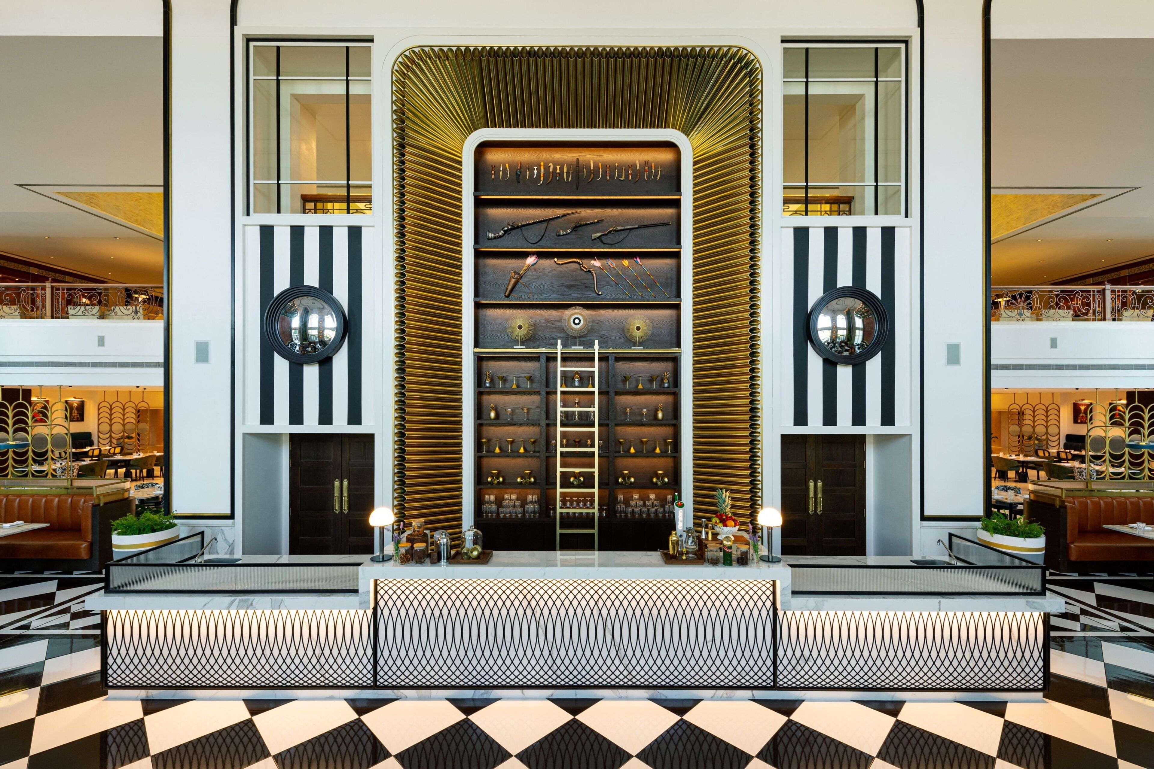 A lobby with a central display of trophies and awards, flanked by two large decorative mirrors and a patterned floor.