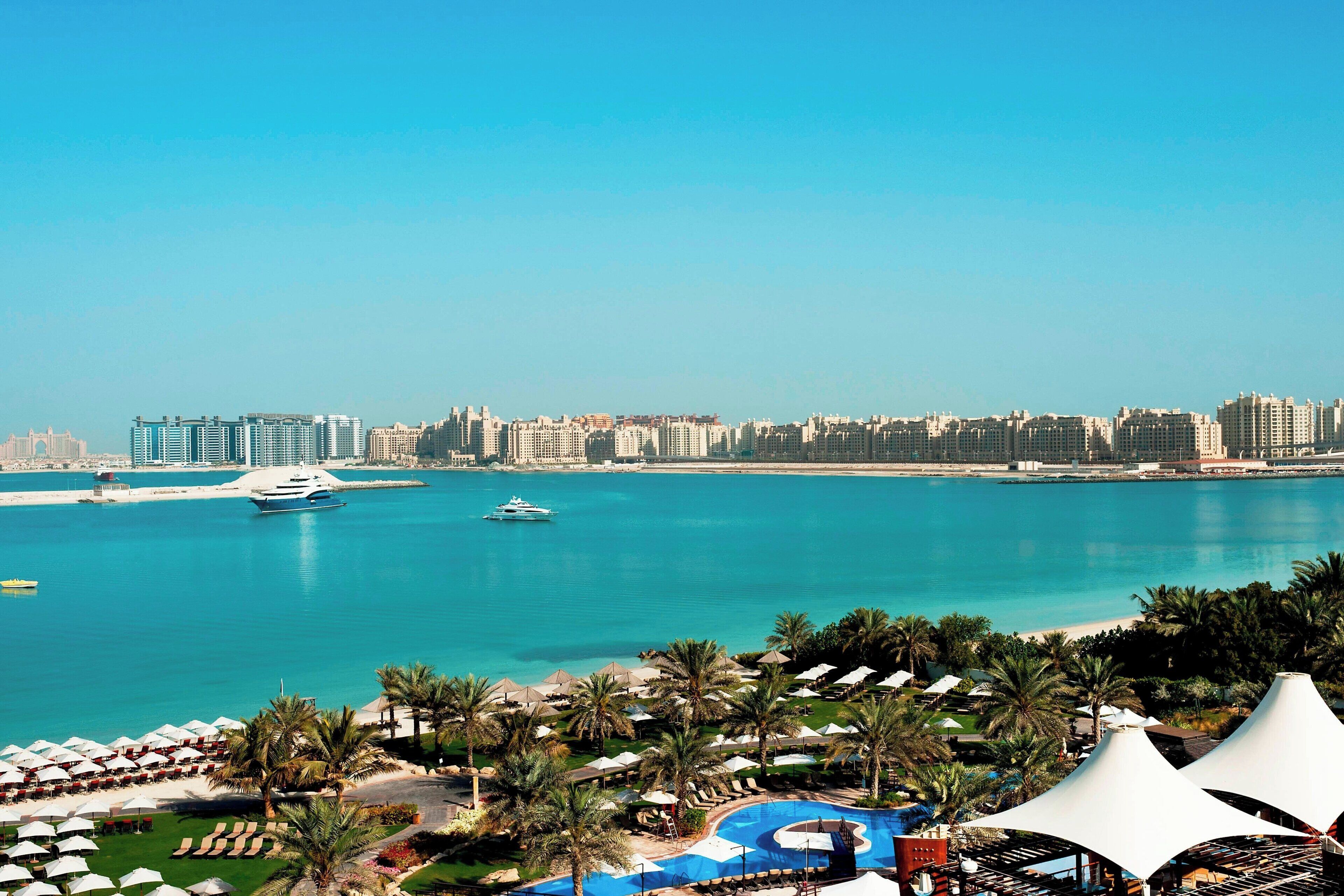 Ein Resort mit Pool, Palmen und Blick auf die Skyline der Stadt.