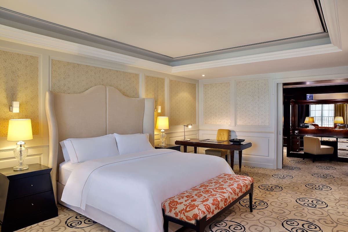 Une chambre d’hôtel avec un grand lit, des lampes de chevet, un bureau et une chaise.