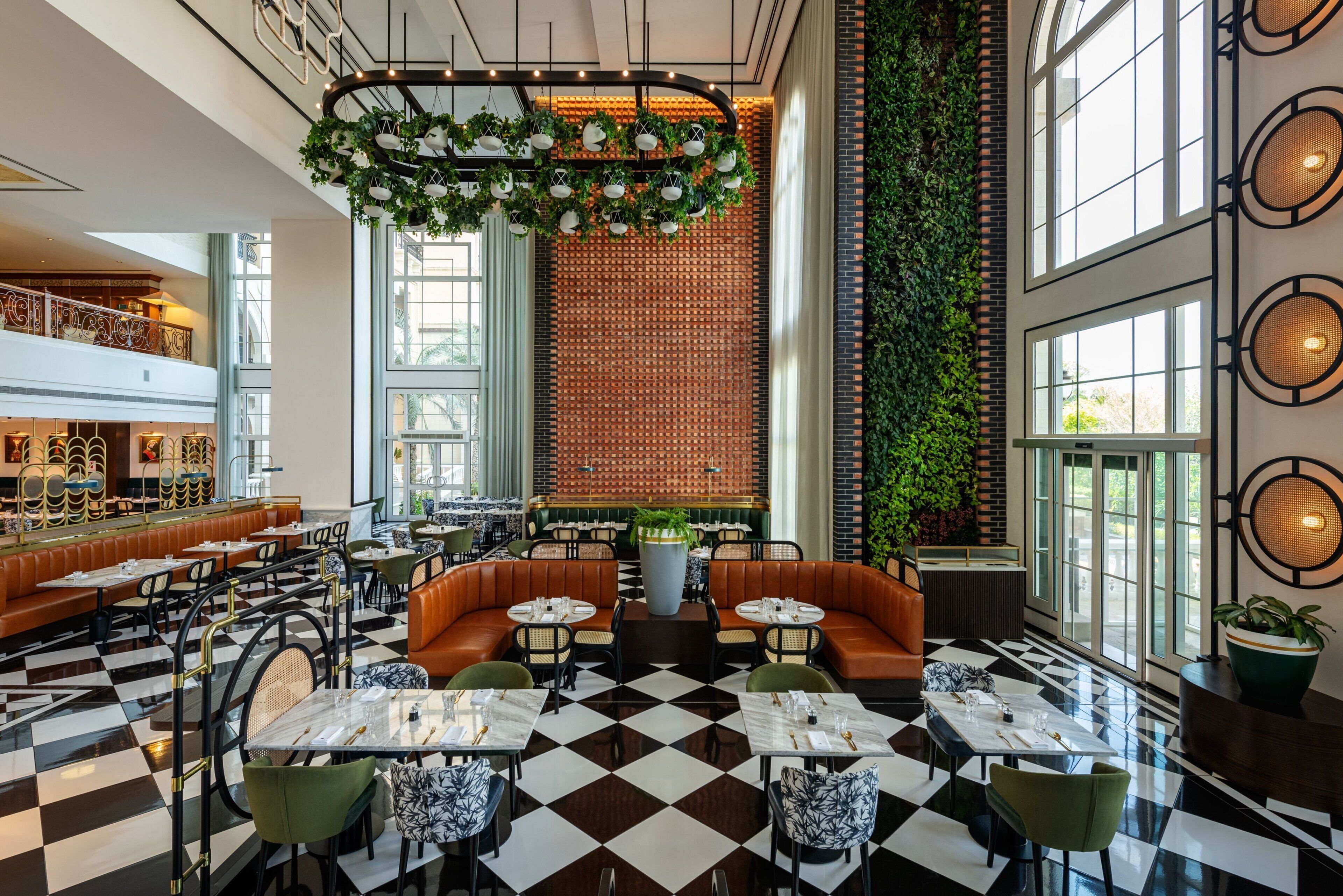 A spacious restaurant with a checkered floor, multiple seating areas including a large booth and round tables, and a decorative hanging light fixture.