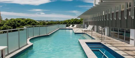 Una piscina al aire libre, sillones reclinables de piscina