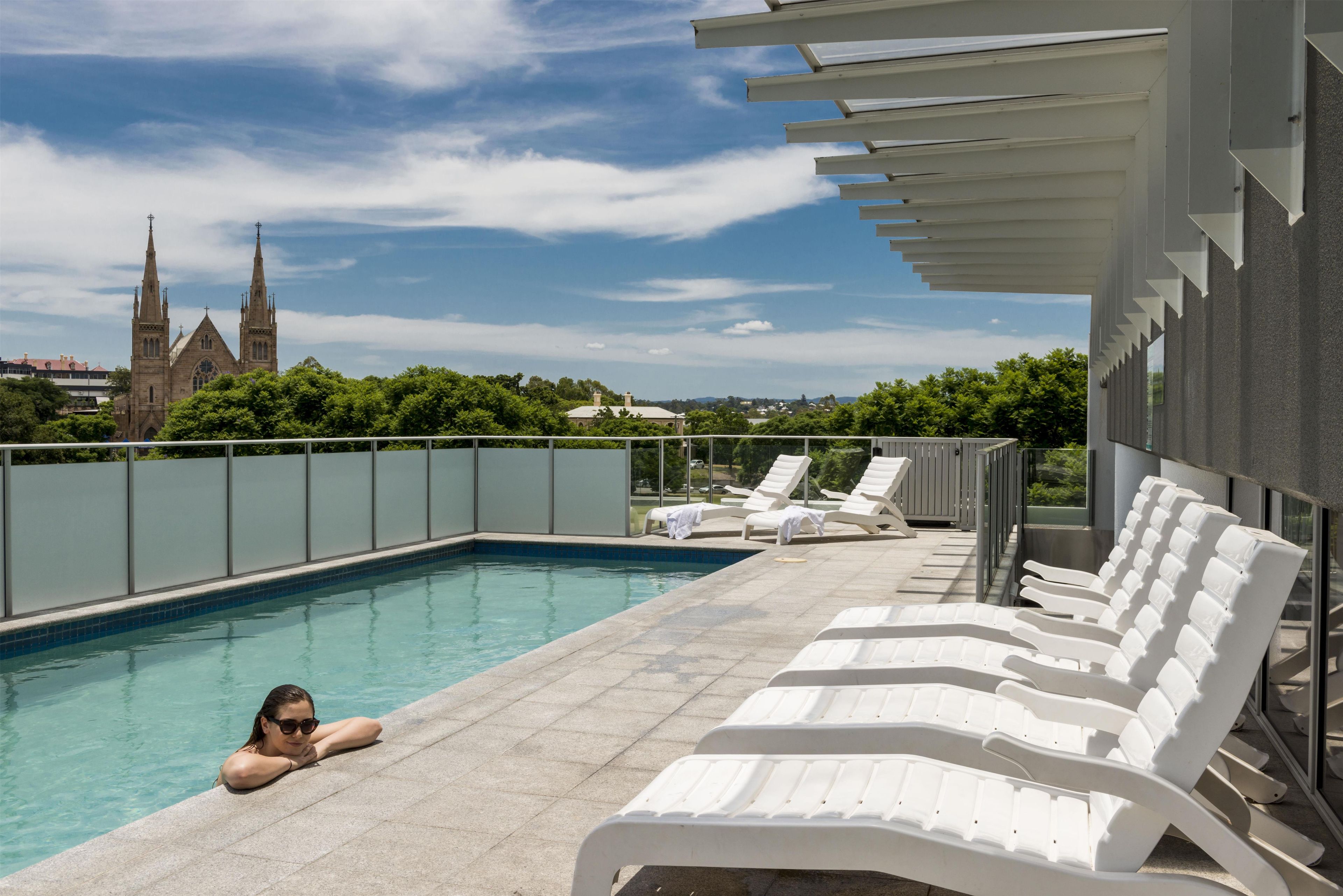 A swimming pool with lounge chairs and a view of a church tower.