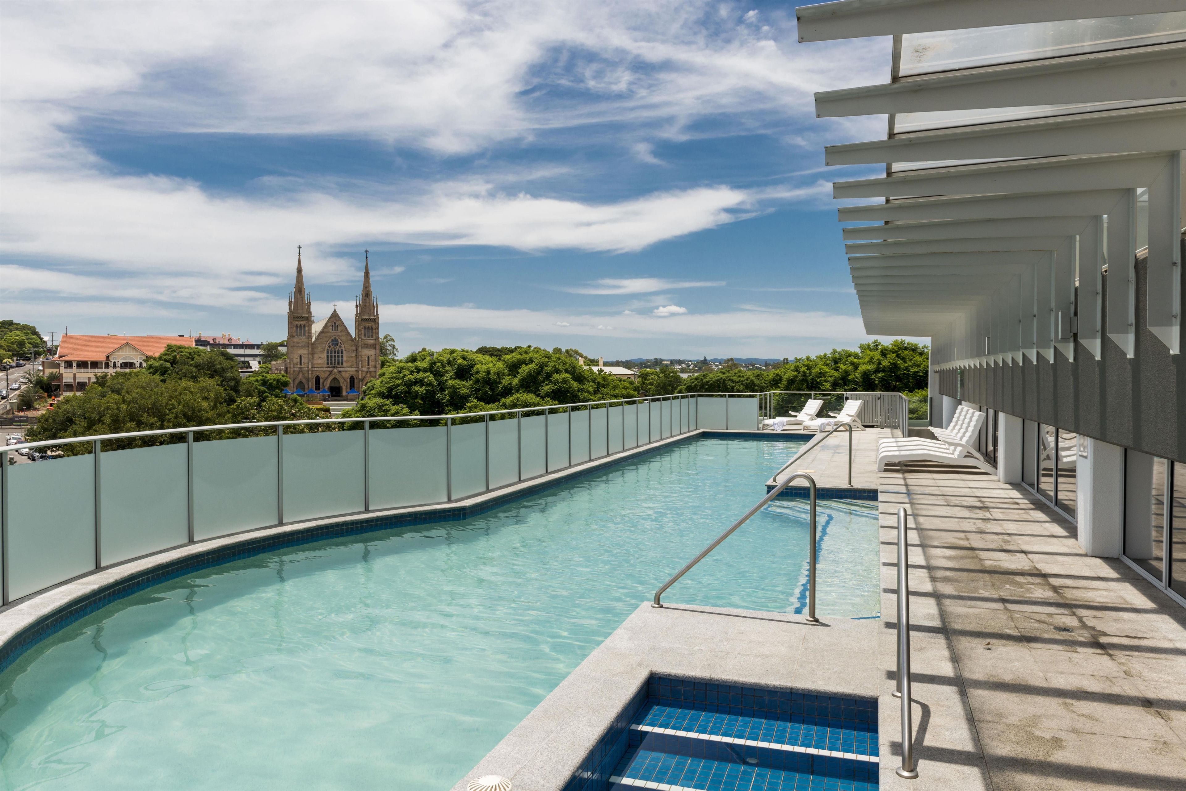 A swimming pool with a view of a church and greenery.