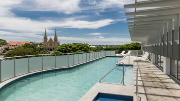 A swimming pool with a view of a church and greenery.