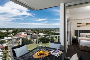 Un balcón con una mesa dispuesta para el desayuno, una cama y vistas a la ciudad.