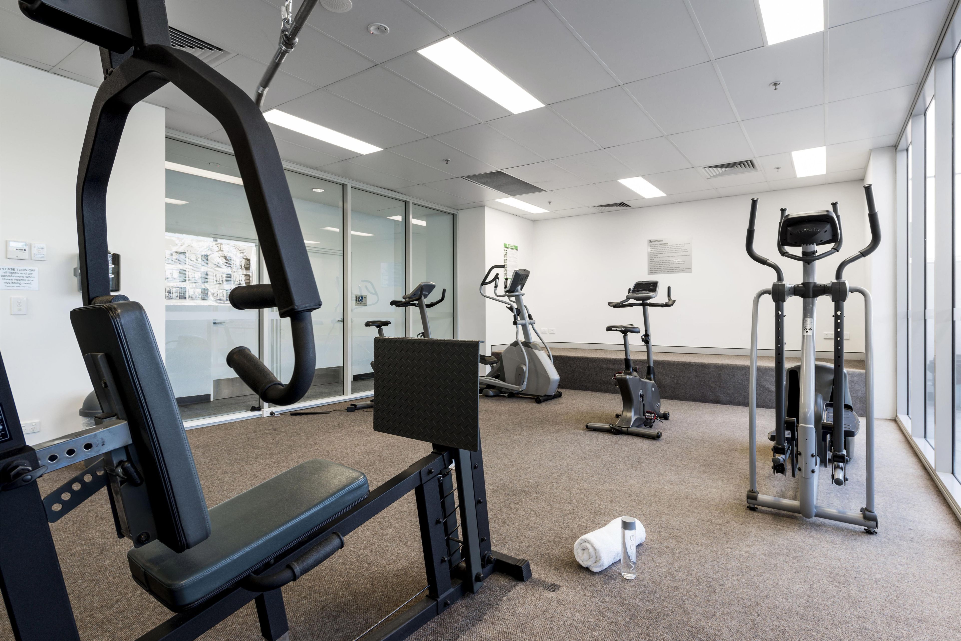 A gym with various exercise equipment, including a treadmill, elliptical, and weight machines.