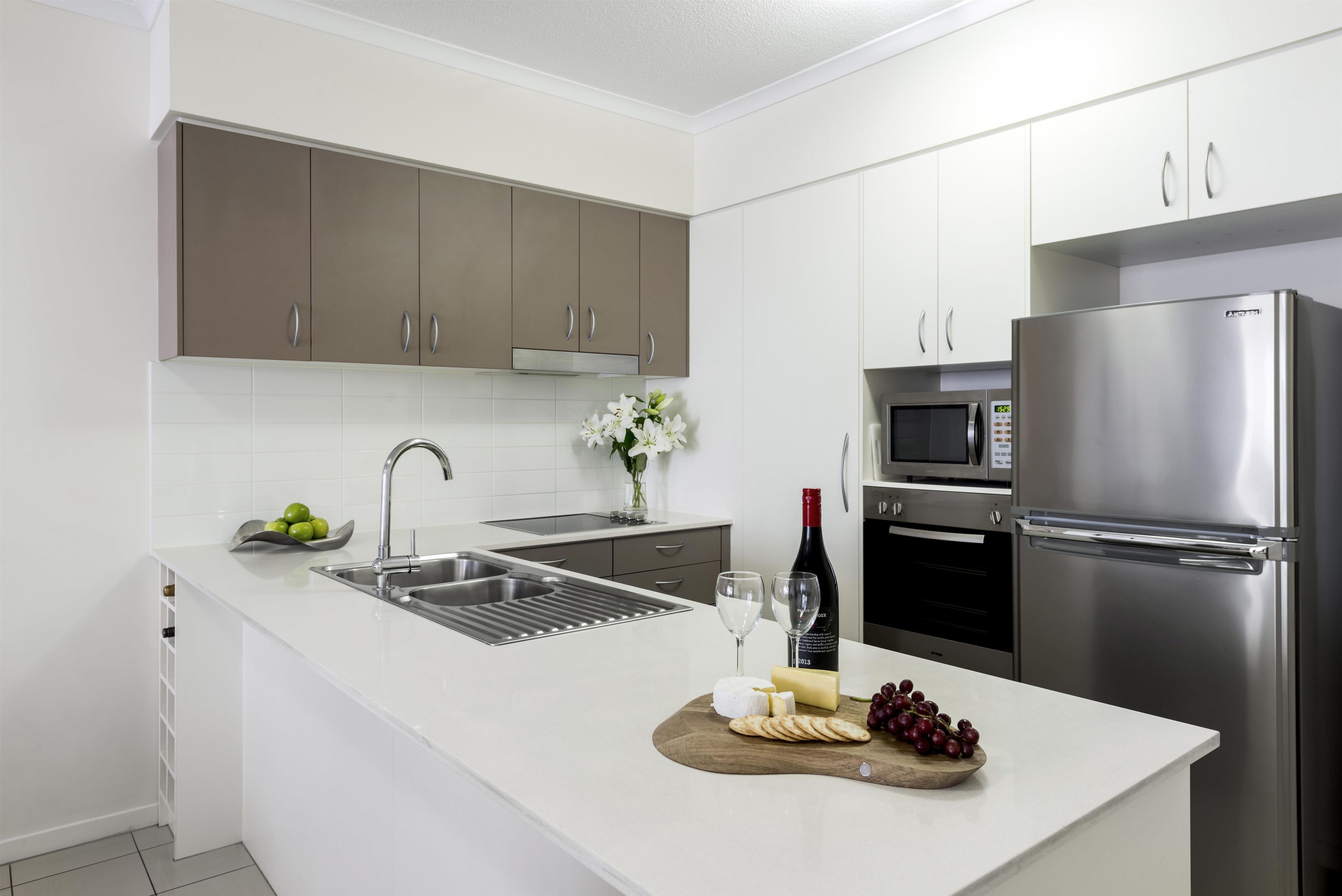 A modern kitchen with stainless steel appliances, a built-in oven, and a wine bottle.