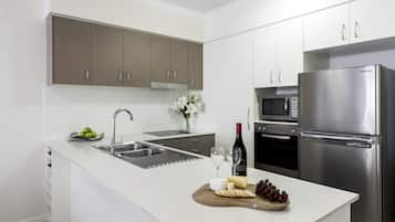 A modern kitchen with stainless steel appliances, a built-in oven, and a wine bottle.
